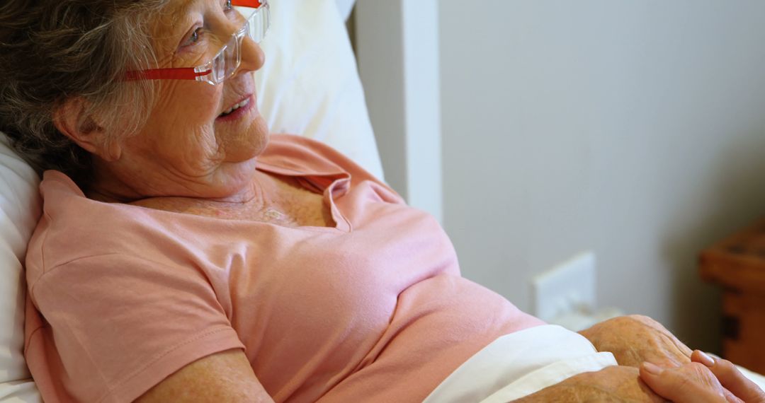 Elderly Woman Resting in Bed Wearing Pink Shirt and Red Glasses - Free Images, Stock Photos and Pictures on Pikwizard.com