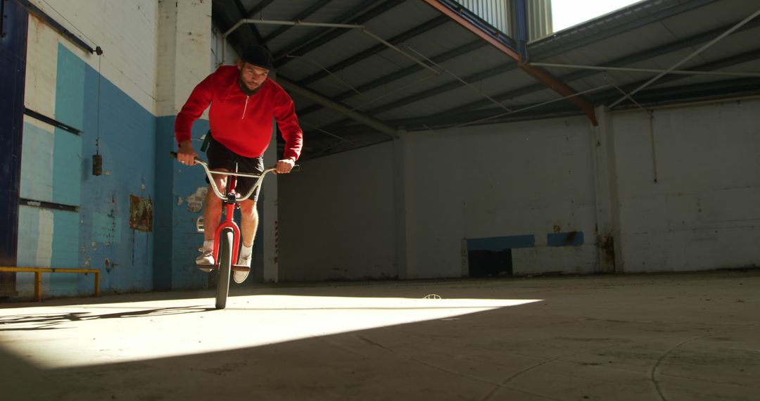 Man Riding BMX Bike In Empty Warehouse With Sunlight - Free Images, Stock Photos and Pictures on Pikwizard.com