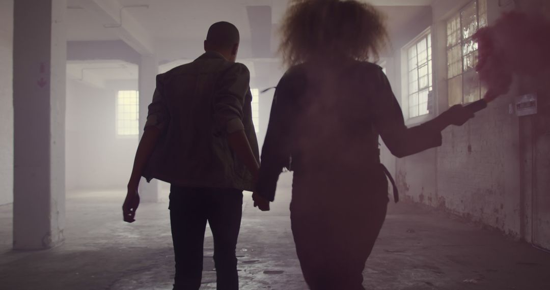 Back View of Couple Holding Hands with Smoke Bomb in Abandoned Warehouse - Free Images, Stock Photos and Pictures on Pikwizard.com