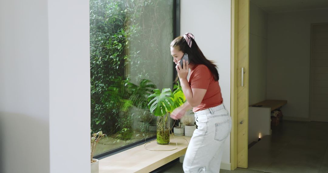 Woman Chatting on Phone Near Window with Monstera Plant