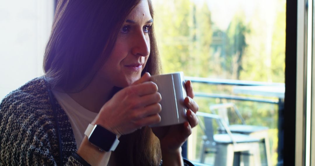 Young Woman Enjoying Coffee by Sunlit Window in Cozy Environment - Free Images, Stock Photos and Pictures on Pikwizard.com