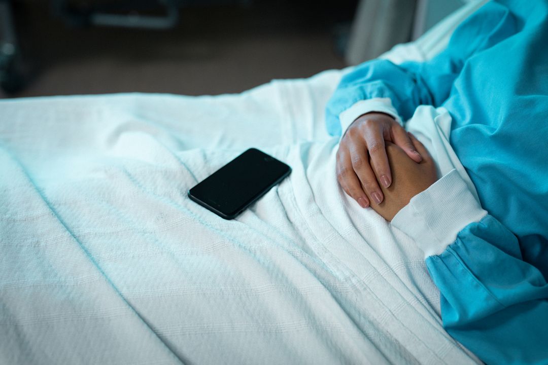 Biracial female patient lying on hospital bed with smartphone - Free Images, Stock Photos and Pictures on Pikwizard.com