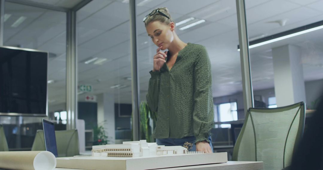 Architect Reviewing Scale Model in Modern Office