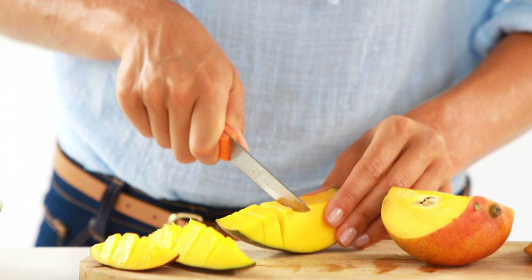 Person Cutting Fresh Mango on Wooden Board in Kitchen - Free Images, Stock Photos and Pictures on Pikwizard.com