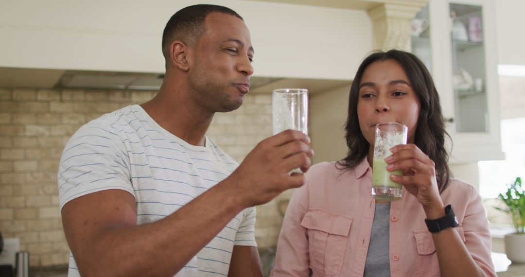 Happy Couple Enjoying Fresh Smoothie in Kitchen Together