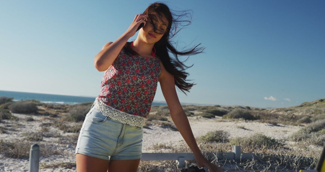 Young Happy Woman Enjoying Windy Day on Beach with Ocean in Background - Free Images, Stock Photos and Pictures on Pikwizard.com