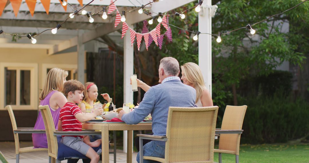 Family Enjoying Outdoor Dining Under Festive Lights - Free Images, Stock Photos and Pictures on Pikwizard.com