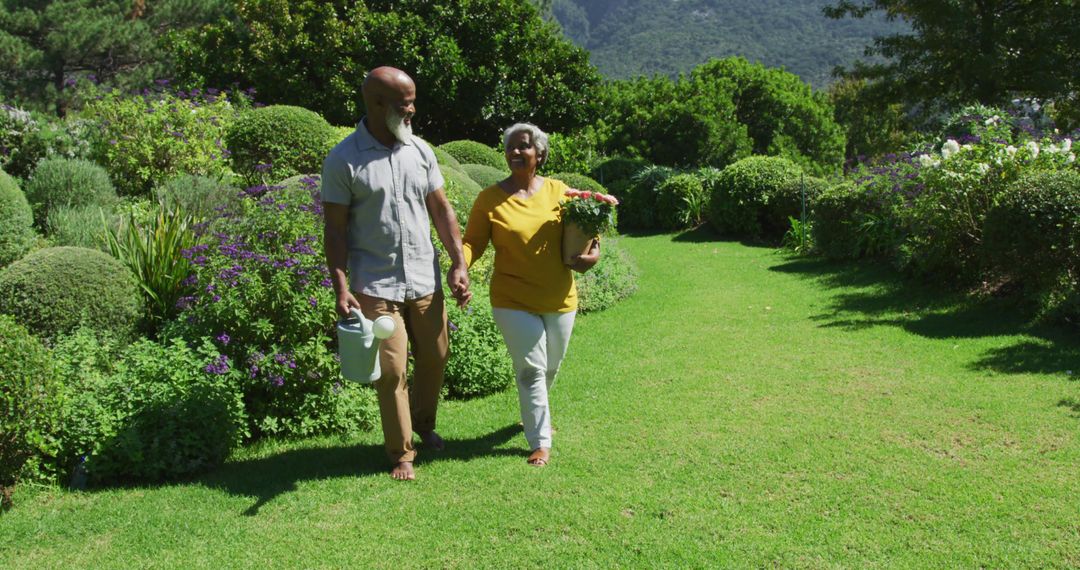 African american senior couple smiling while holding hands and walking together in the garden - Free Images, Stock Photos and Pictures on Pikwizard.com