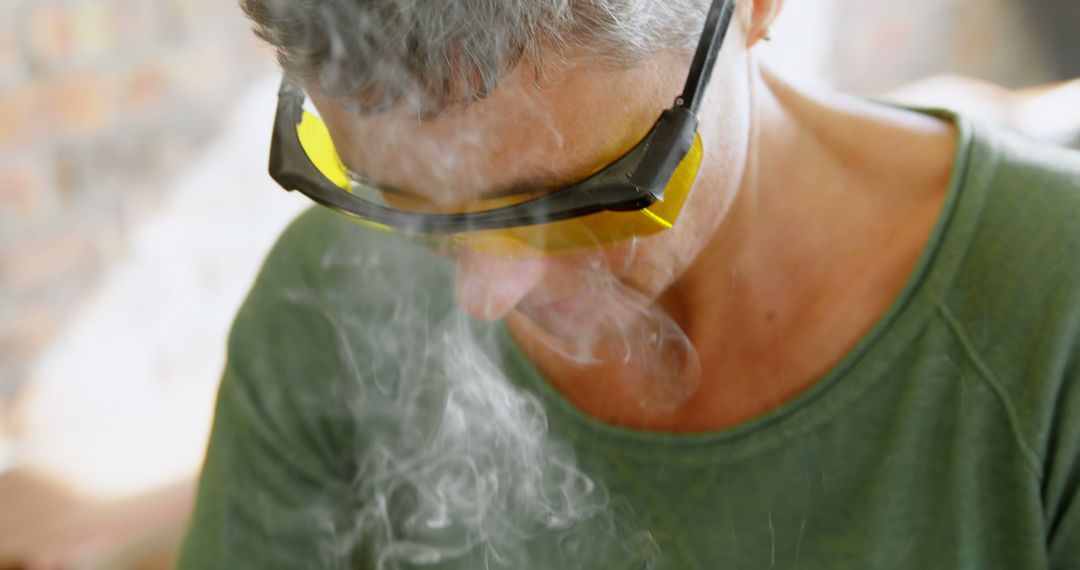 A man diligently uses safety gear during a smoky task like soldering or woodworking. - Free Images, Stock Photos and Pictures on Pikwizard.com