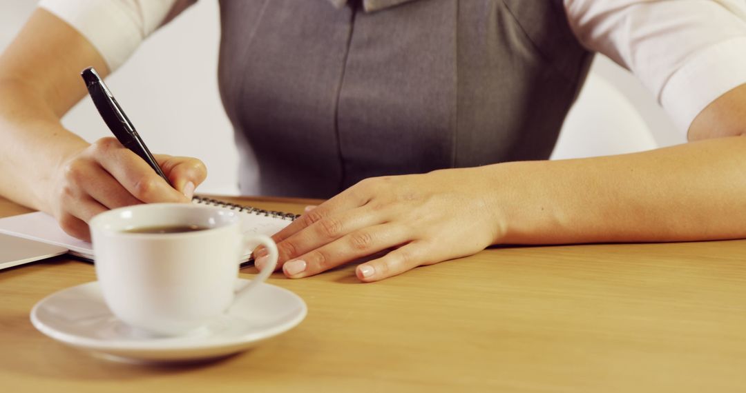 Professional Woman Writing Notes at Desk with Coffee Cup - Free Images, Stock Photos and Pictures on Pikwizard.com