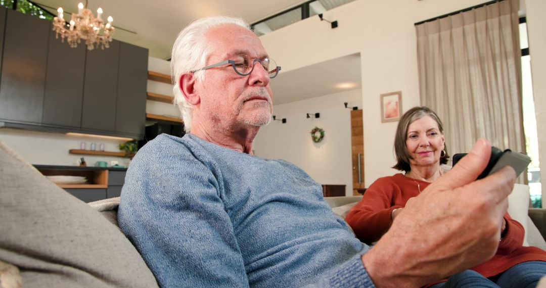 Senior Couple Relaxing on Modern Fabric Couch with Remote Control