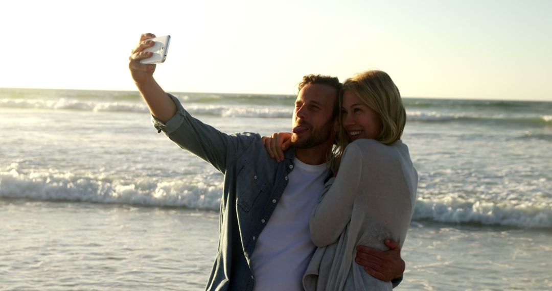 Happy Couple Taking Selfie by the Ocean at Sunset - Free Images, Stock Photos and Pictures on Pikwizard.com