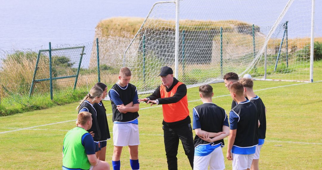 Soccer Coach Giving Strategy Talk to Young Players on Field