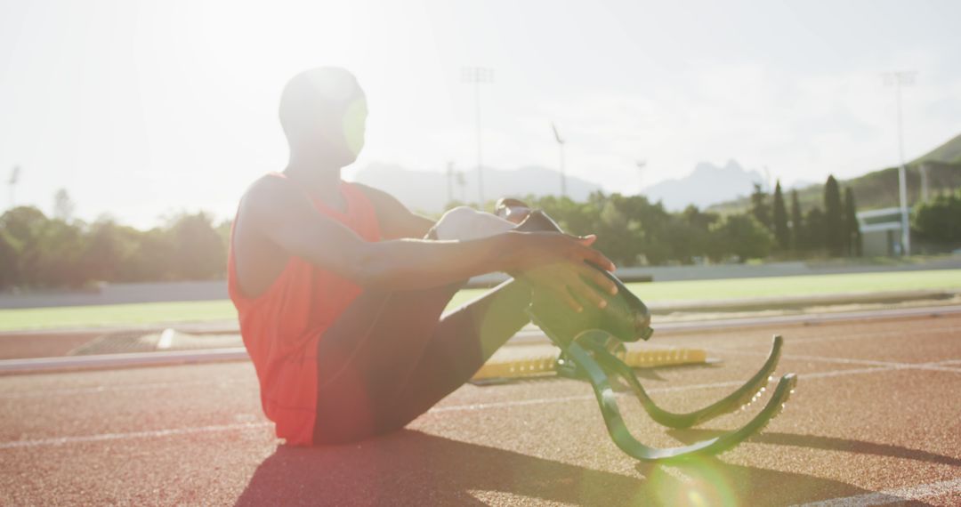 Paralympic Athlete with Prosthetic Legs Sitting on Track in Sunlight - Free Images, Stock Photos and Pictures on Pikwizard.com