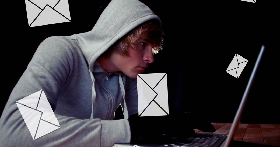 Young Man in Hoodie Engaging in Digital Activities with Laptop