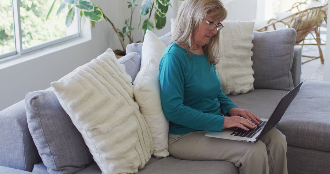 Senior Woman Sitting on Sofa Using Laptop at Home - Free Images, Stock Photos and Pictures on Pikwizard.com