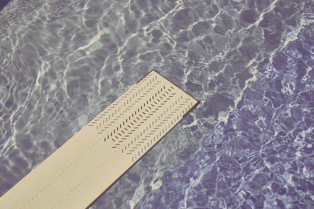 Diving Board Extending Over Sparkling Blue Pool Water