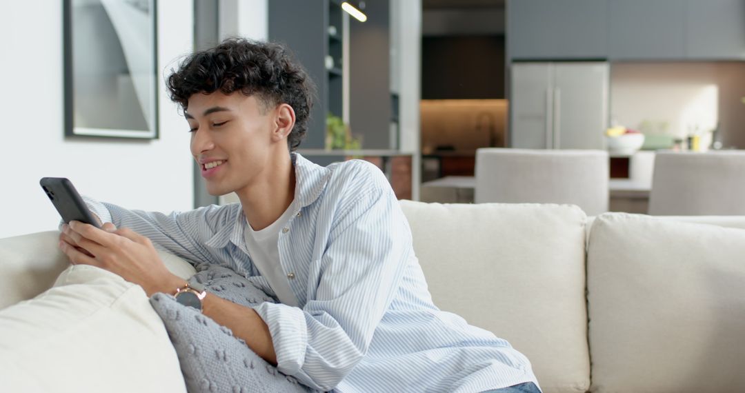 Young Man Relaxing on Modern Sofa Using Smartphone