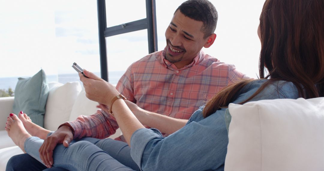 Diverse Couple Relaxing on a Sofa Holding Television Remote
