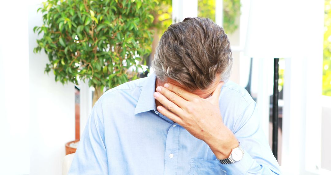 Stressed Man Holding Face in Office Environment