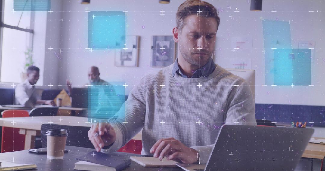 Mid-adult man typing at coworking desk with laptop and coffee, collaborating in modern shared worksp