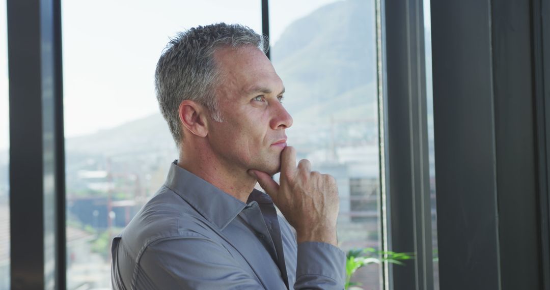 Thoughtful Mature Man Looking Out Window in Office - Free Images, Stock Photos and Pictures on Pikwizard.com