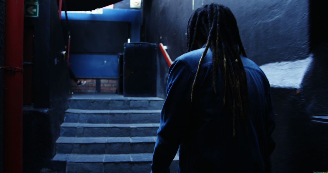 Man with Dreadlocks Ascending Stone Stairs Outdoors