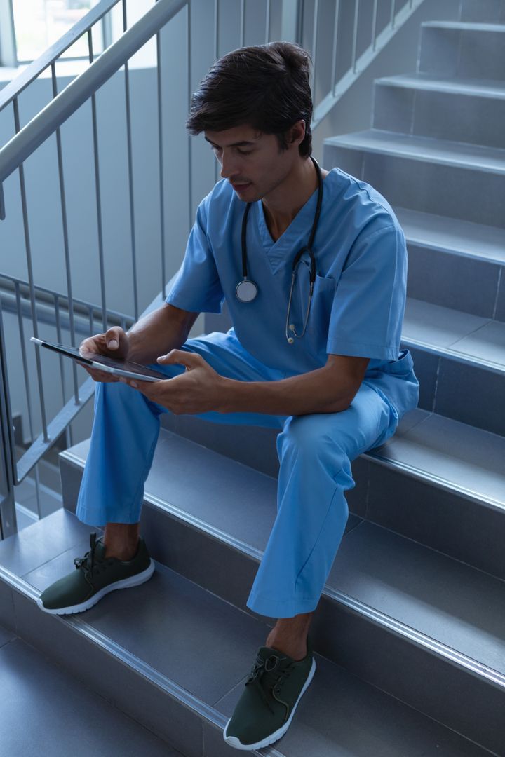 Male surgeon using digital tablet on stairs at hospital - Free Images, Stock Photos and Pictures on Pikwizard.com