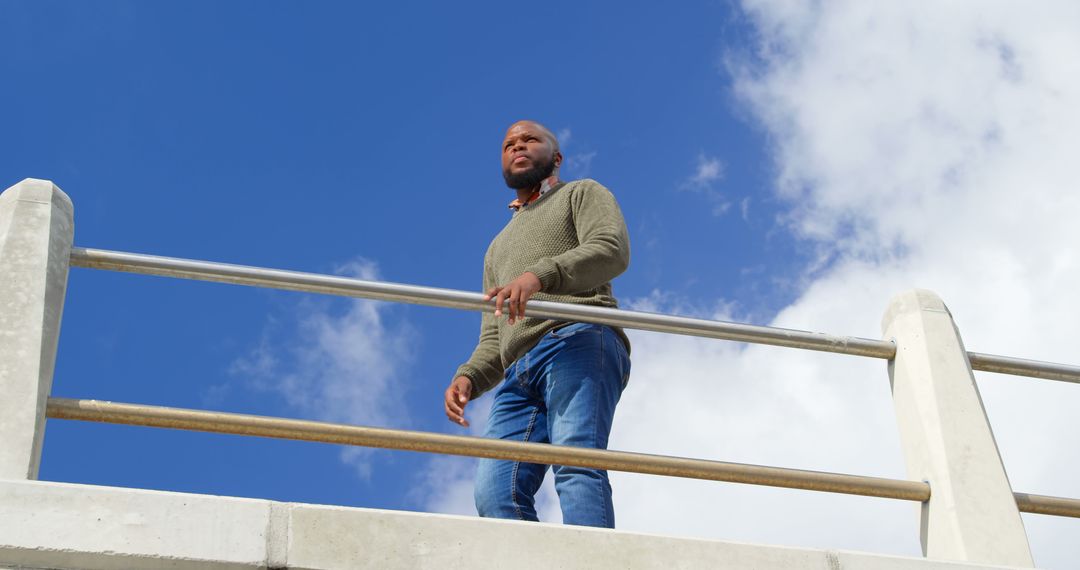 Confident man standing on bridge against blue sky - Free Images, Stock Photos and Pictures on Pikwizard.com