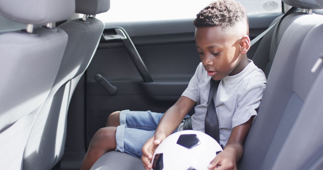 Boy with Soccer Ball Buckling Up in Car for Safe Journey