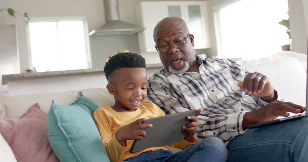 Grandfather and Grandson Using Tablet Together on Couch at Home - Free Images, Stock Photos and Pictures on Pikwizard.com