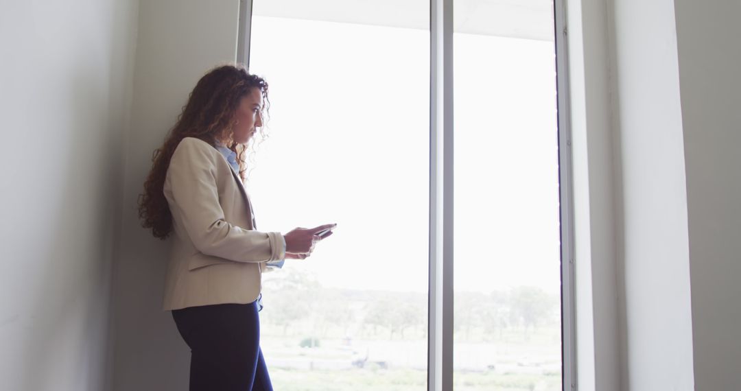 Businesswoman Using Smartphone by Window in Office Setting