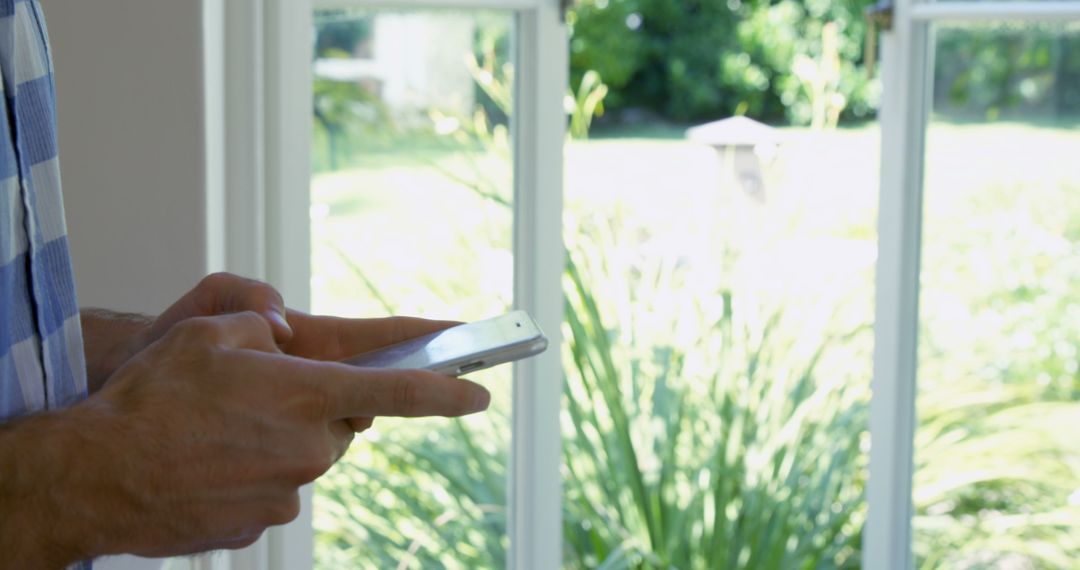 Man Using Smartphone by Window in Daylight - Free Images, Stock Photos and Pictures on Pikwizard.com