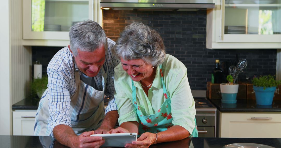Senior Couple Using Tablet in Modern Kitchen, Laughing Together