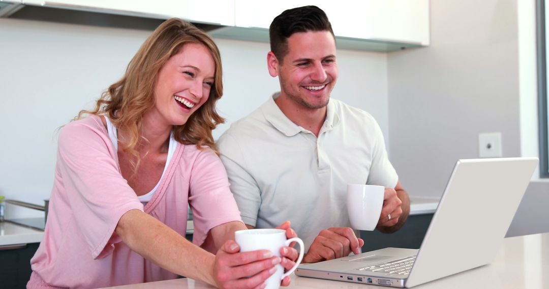 Happy Couple Enjoying Coffee While Using Laptop at Home