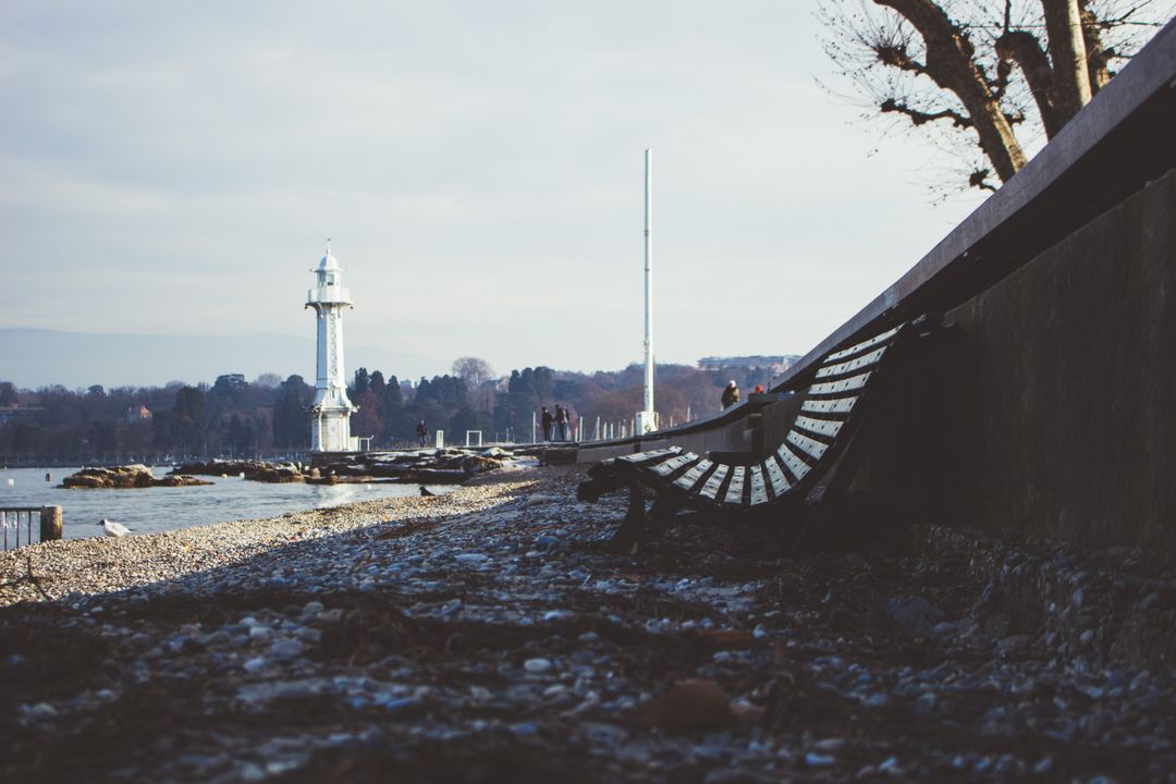 Tranquil Lakeside Promenade with Lighthouse and Bench in Winter - Free Images, Stock Photos and Pictures on Pikwizard.com