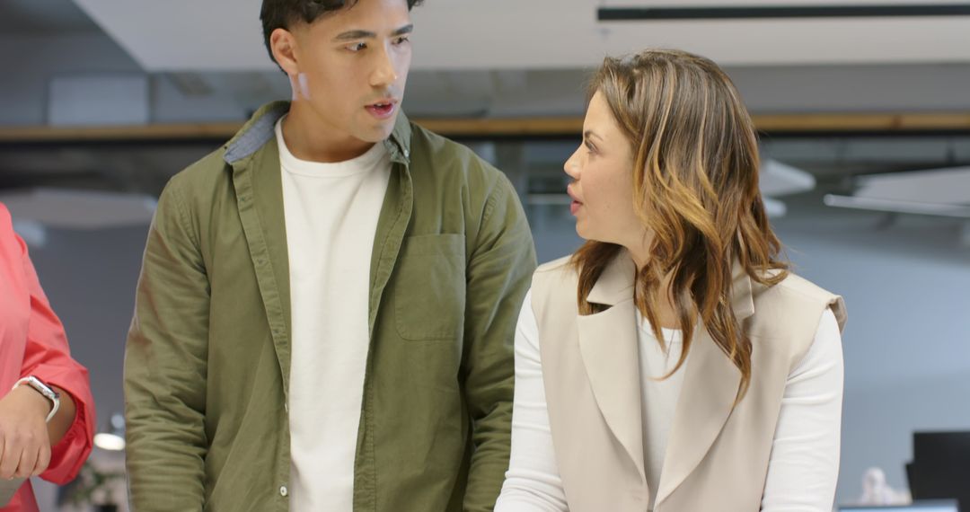 Diverse coworkers collaborating at open-plan workstation discussing project ideas