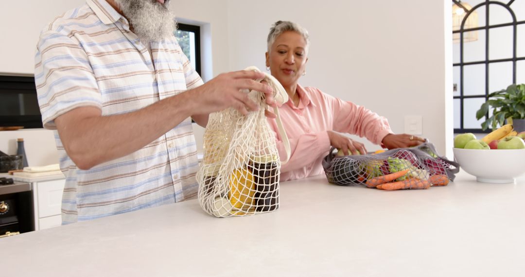 Eco-Friendly Senior Couple Arranging Groceries with Reusable Mesh Bags