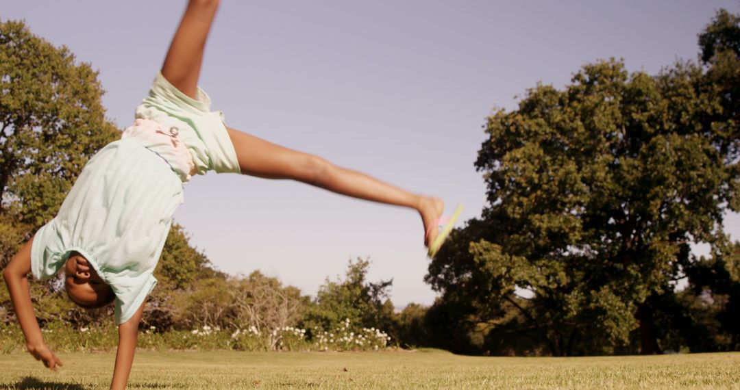 Young Girl Doing Cartwheel on Grassy Field on Sunny Day - Free Images, Stock Photos and Pictures on Pikwizard.com