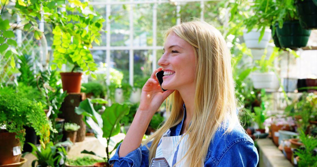 Smiling Woman Talking on Phone in Greenhouse Surrounded by Plants - Free Images, Stock Photos and Pictures on Pikwizard.com