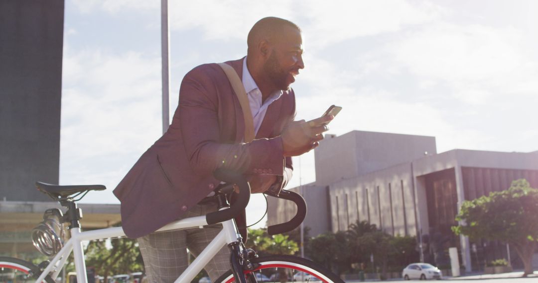 African American Man Using Smartphone While Sitting on Bicycle in Urban Setting