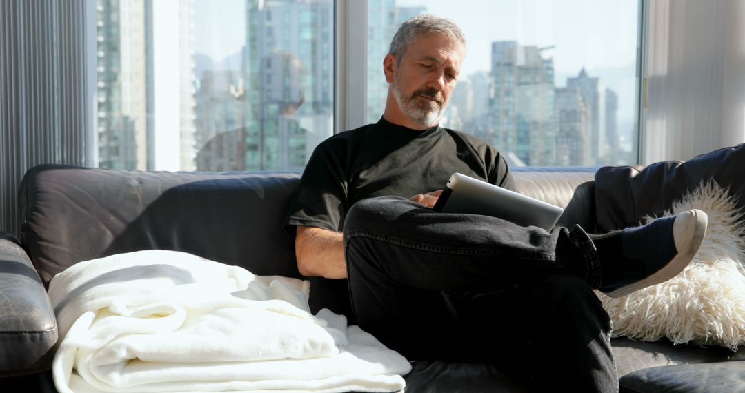 Middle-Aged Man Relaxing with Tablet in Modern Apartment - Free Images, Stock Photos and Pictures on Pikwizard.com