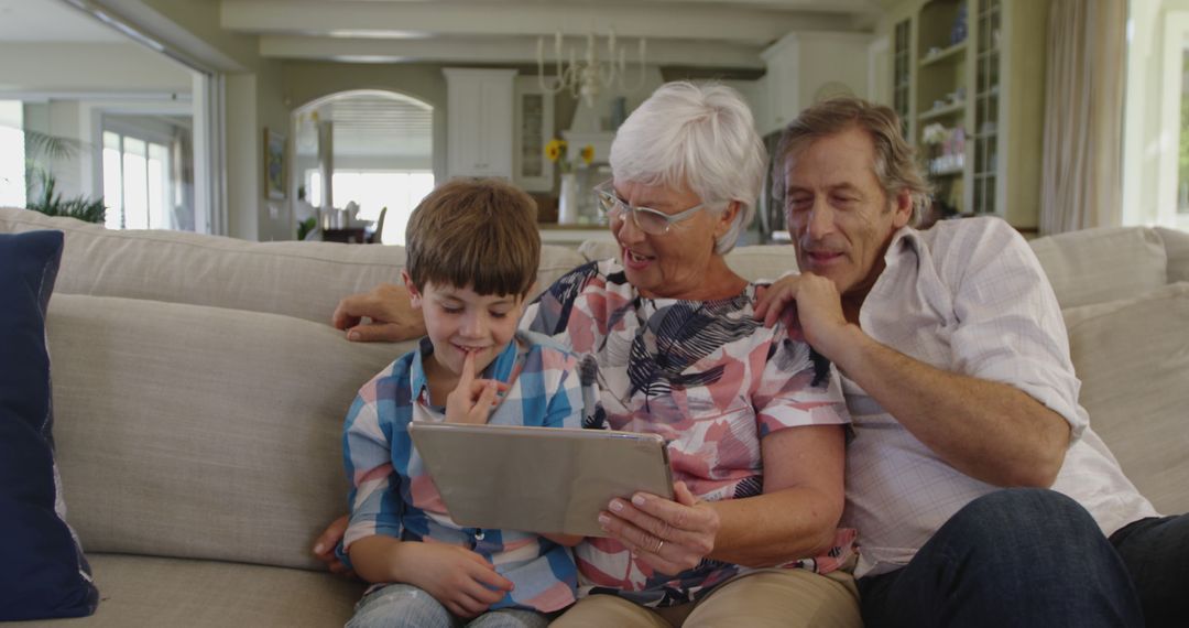 Grandparents and Grandchild Using Tablet Sitting on Couch in Living Room - Free Images, Stock Photos and Pictures on Pikwizard.com