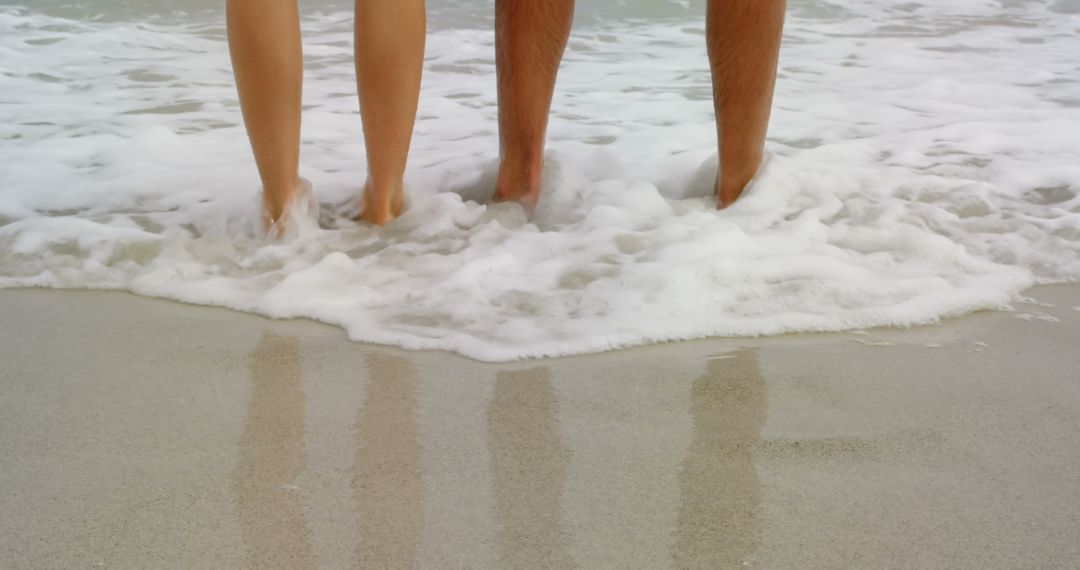 Low Section of Couple Entering Ocean Waves