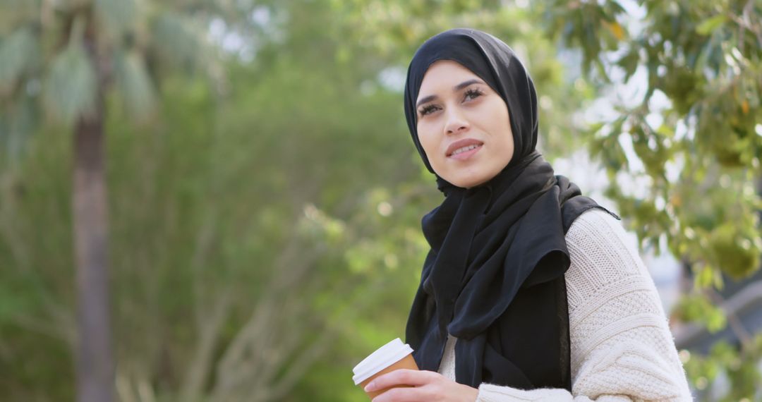 Young Woman Wearing Hijab Enjoying Coffee Outdoors - Free Images, Stock Photos and Pictures on Pikwizard.com