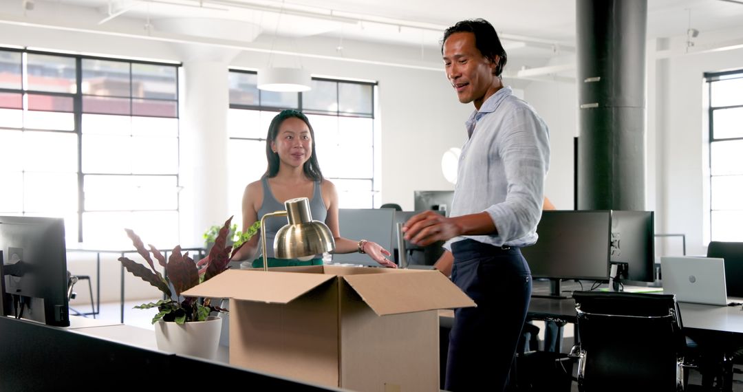 Colleagues Unpacking Box with Office Items in Modern Workspace