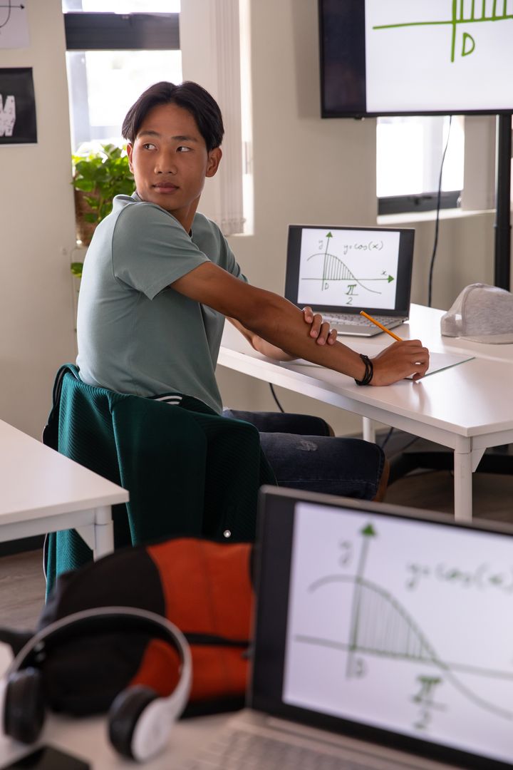 Asian Teenage Student Engaged in Classroom with Technology Tools