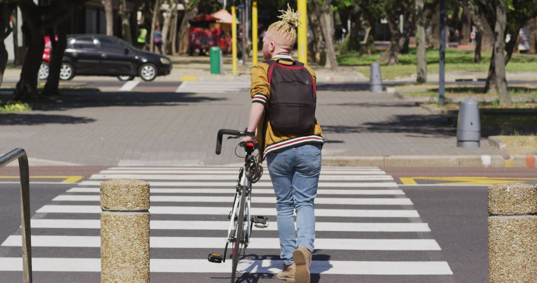 Young person with bike crossing street at city pedestrian crossing - Free Images, Stock Photos and Pictures on Pikwizard.com