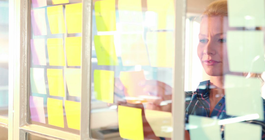 Businesswoman Planning with Sticky Notes on Glass Wall - Free Images, Stock Photos and Pictures on Pikwizard.com