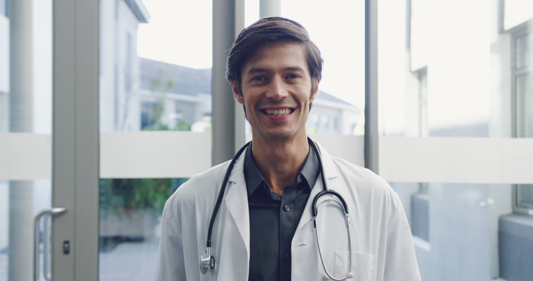 Smiling Male Doctor with Stethoscope in Hospital Corridor - Free Images, Stock Photos and Pictures on Pikwizard.com